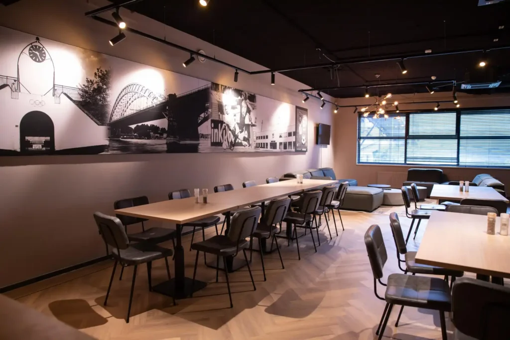 nterior of a modern supermarket with black linear ceiling lights and black track spotlights illuminating aisles of chilled and frozen foods, wine, and other grocery products. The ceiling features exposed metal beams and an air conditioning unit.